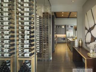 Wine cellar with glass facing door to hallway that leads to kitchen area.