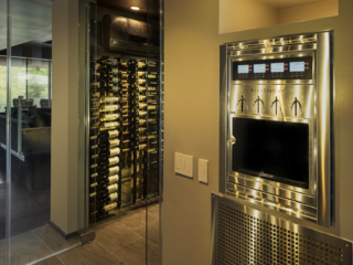 Contemporary wine room designed with glass doors and metal racking to match sleek kitchen appliances.