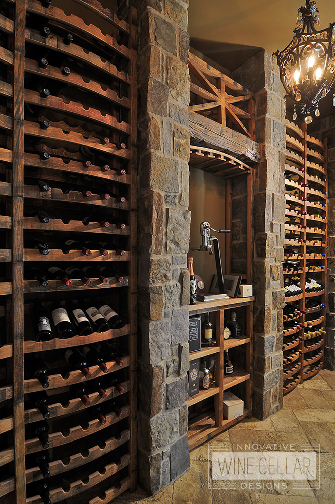 Under stairs custom wine cellar using reclaimed wine barrels & antique decor, created by Innovative Wine Cellar Designs.
