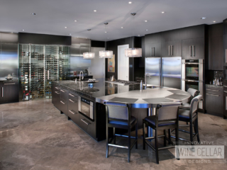 Recessed glass wine cellar in kitchen wall with stainless steel accents matching modern appliances.